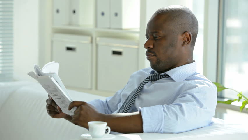 Handsome African-American businessman reading newspaper on coffee break
