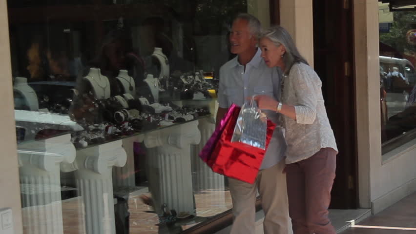 Couple looking at shop window and walk with shopping bags