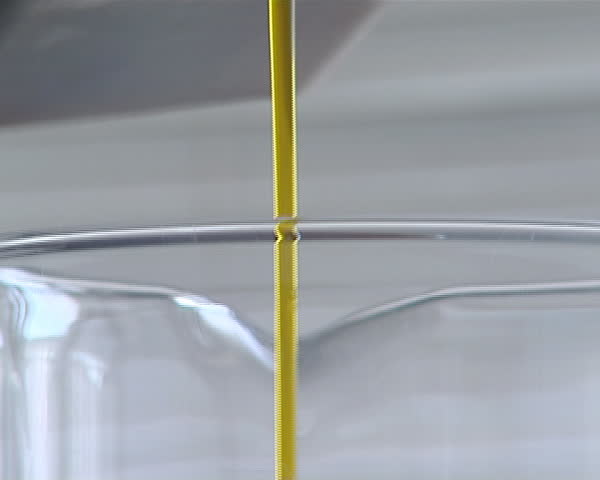 poured rape oil biodiesel stream flowing from bottle into glass flask with capacity meter in liters milliliters
