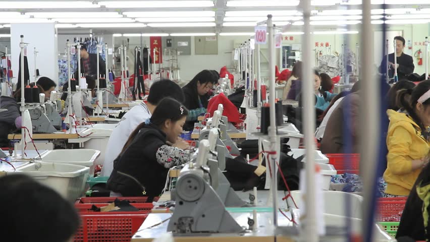 SHENZHEN, CHINA -  JUNE 5:  Wide shot of textile factory workers working. June 5, 2011 in Shenzhen, China