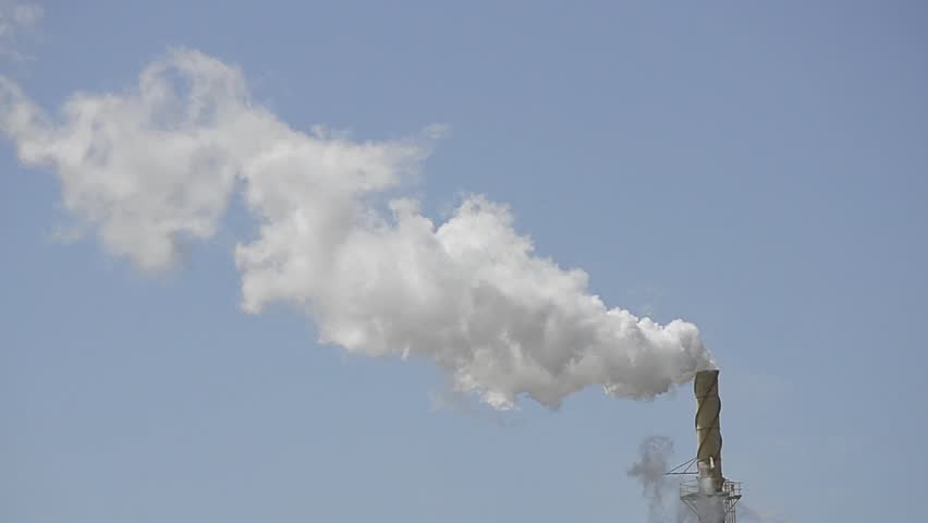 Smoke stack from factory with blue sky in background bellowing white smoke steam pollution