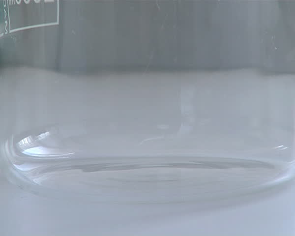 poured rape seed oil biodiesel stream flowing from bottle into glass flask with capacity meter in liters milliliters