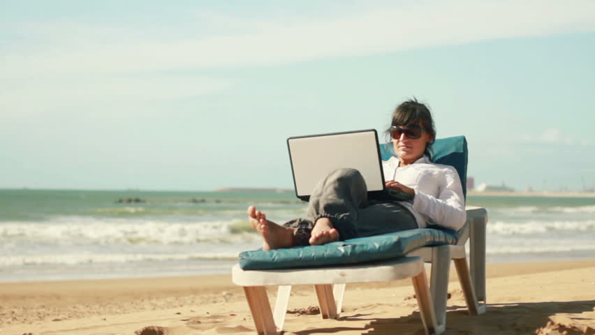 Businesswoman finishing work on laptop and relaxing on sunbed