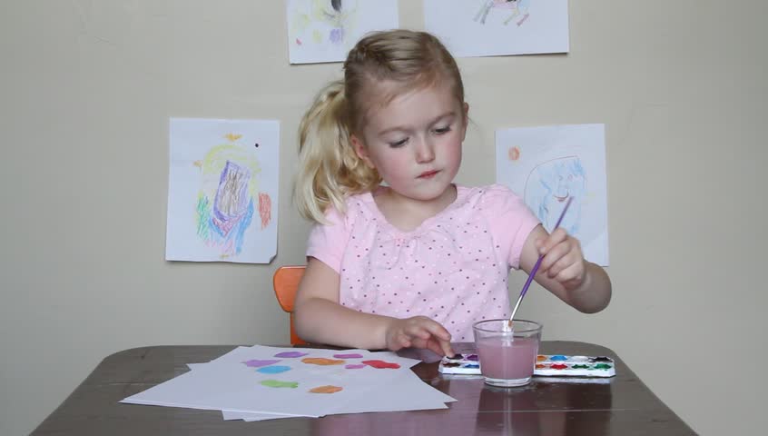 Young child drawing with crayons while sitting at desk