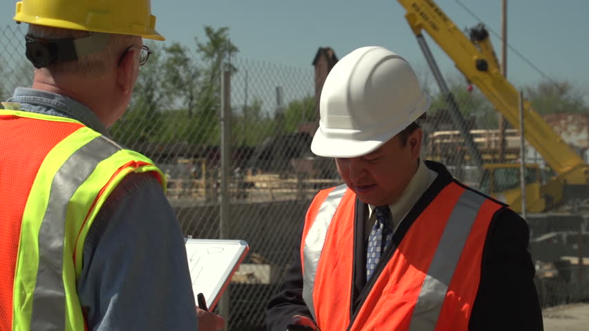 Business man and construction worker talking on site