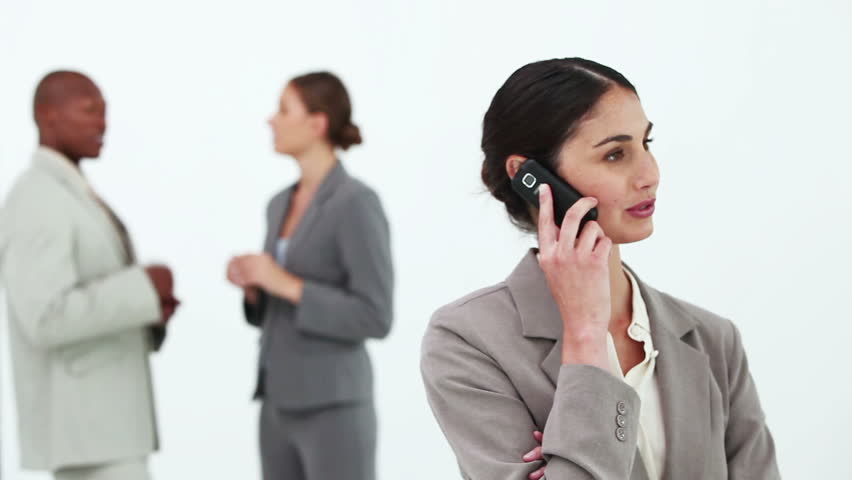 Black hair businesswoman on the phone with co-workers in background
