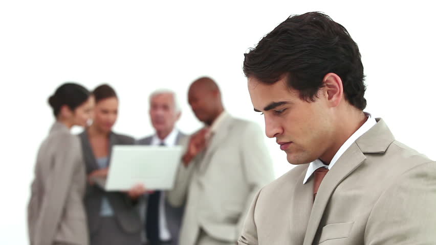Serious businessman with his co-workers in background using a laptop