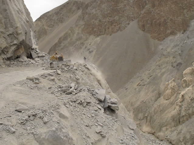Excavator and Truck moving rock and sand to clear the road from Ladakh to Srinagar, Jammu and Kashmir state - India