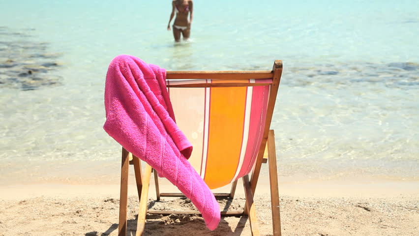 female coming out of sea drying and sitting on deckchair