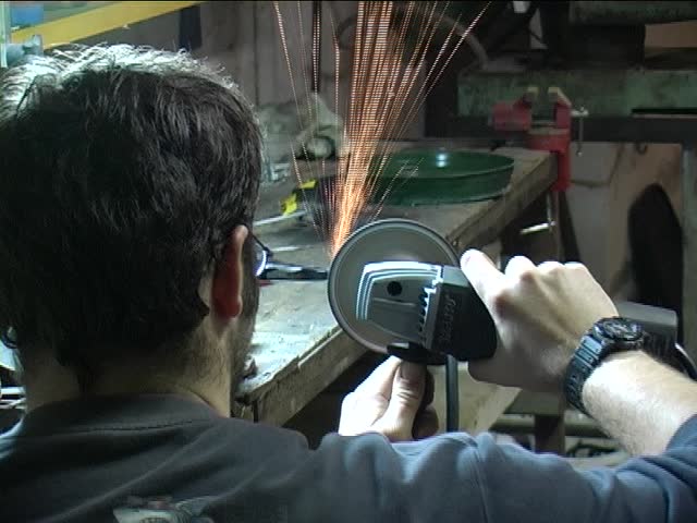 A working man in a workshop using  an electric grinder (PAL)