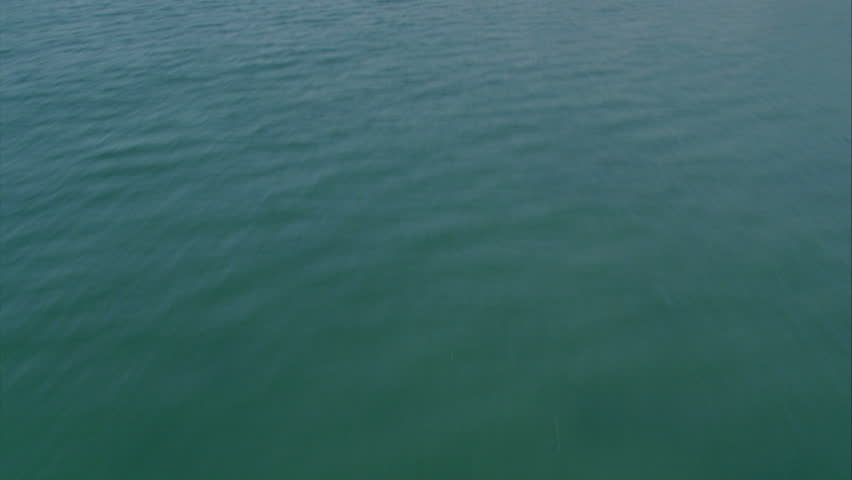 aerial shot flying over the turquoise waves of the Pacific, tilt up to reveal the coastline community circa 2009