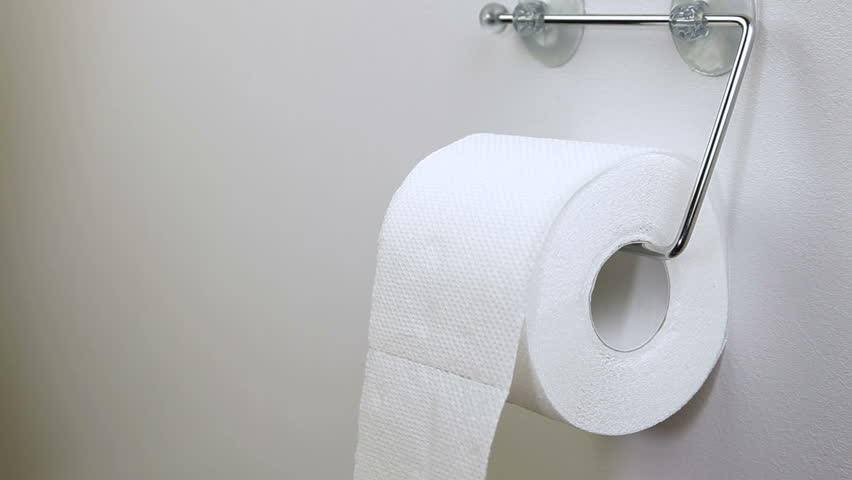 Hand taking sheets of paper from a toilet roll