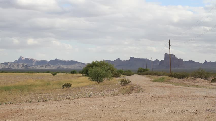 wide angle shot of empty desert dirt road heading up into the mountains, telephone poles. April 13, 2012 in the Sonoran Desert, Arizona.