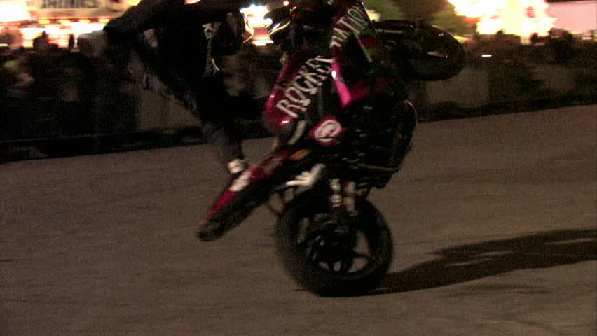 Stunt motorcycle rider doing a spin ride at night. Carnival with bright lights and thrill rides.