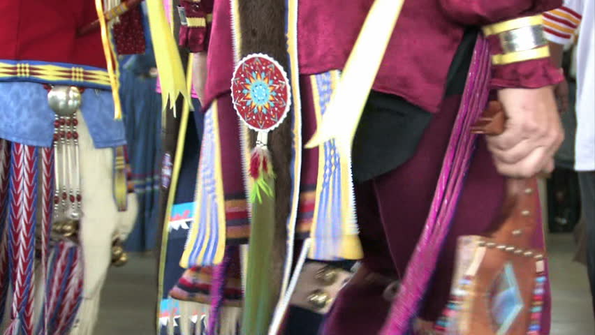 American Indian and re enactment wearing authentic native clothes. Close up of colorful clothes. Pow wow dance demonstration and show. Leather, animal skins and feathers.