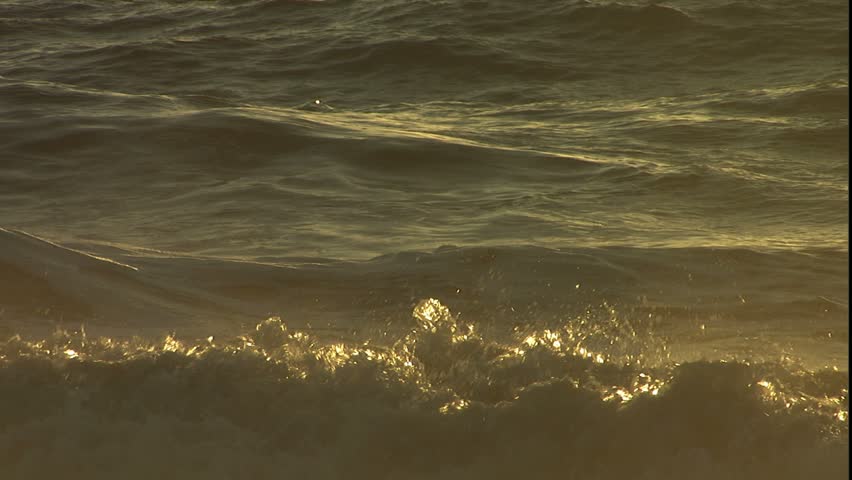 Backlit, cresting waves at sunrise