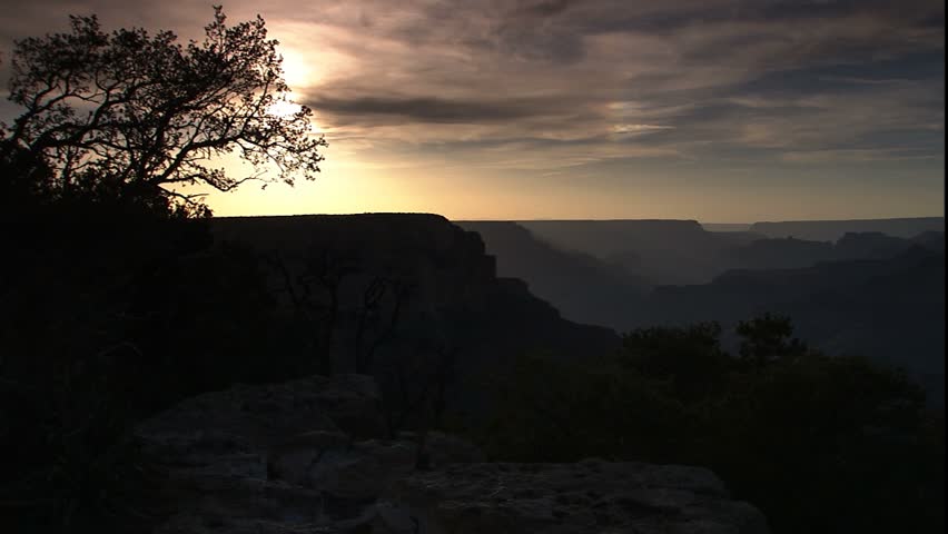 pan across grand canyon in late afternoon hazy sun to canyon framed between a pair of junipers