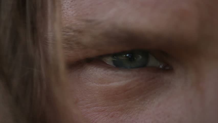 Close up of blond young male eye with hair in foreground.

