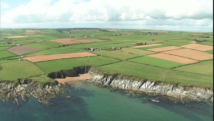 coast and fields with small cove with a couple of boats anchored