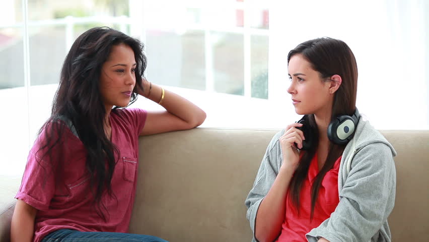Woman chatting with a friend while holding headphones in her living room