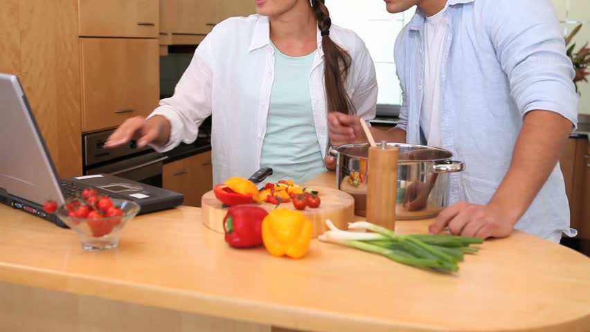 Couple reading a recipe on a laptop to cook in the kitchen