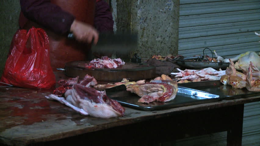Chicken chopper in Chinese Farmers market as she bag pieces and cleans chopping block, Youngshou, China