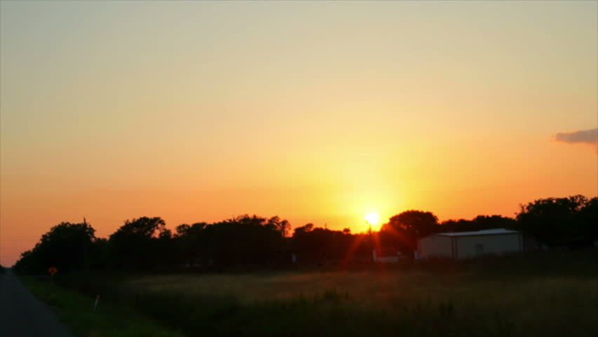 A lazy Texas sun just before sunset appears to follow travelers along a rural stretch of highway.