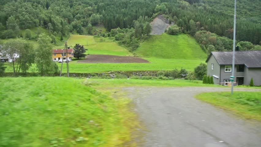 Few country houses among trees at background of mountains, shown in motion