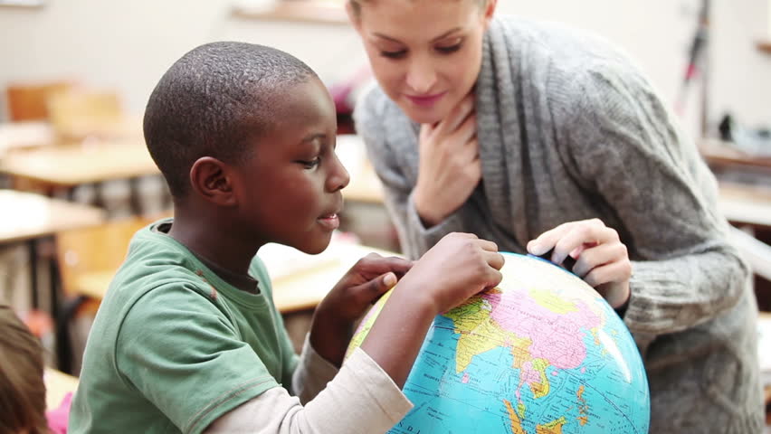 Pupil and teacher looking at a globe in the classroom