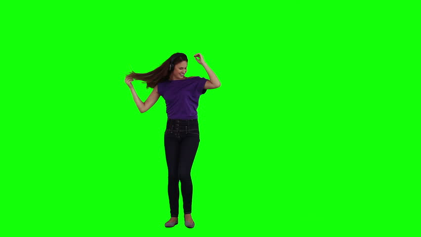 A dancing woman is listening to music on her headphones against a green background