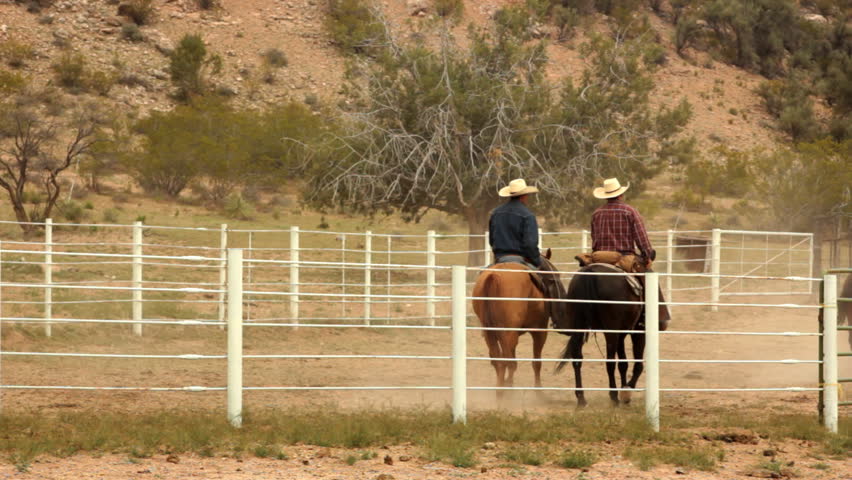 CORNVILLE, AZ - APRIL 23: Two cowboys on horseback ride in a field on April 23, 2011 in Cornville, AZ.