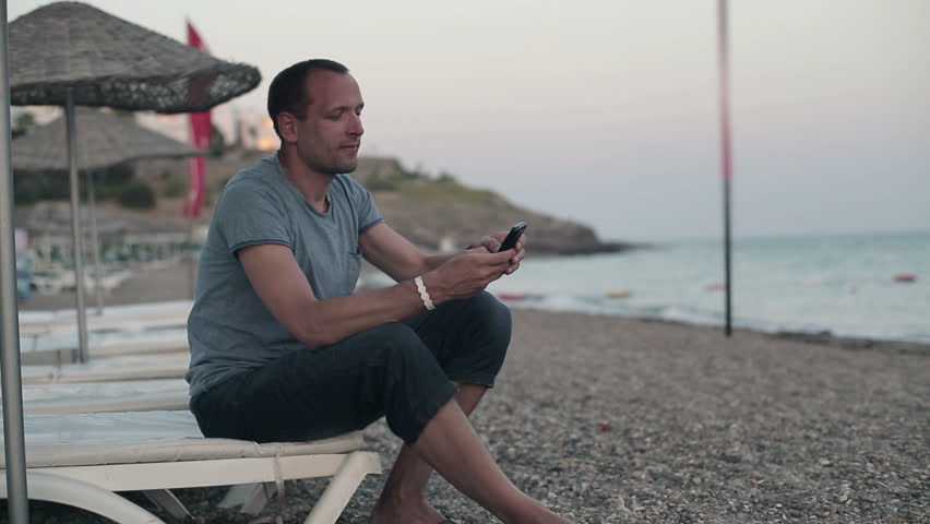 Young man using smartphone on the beach
