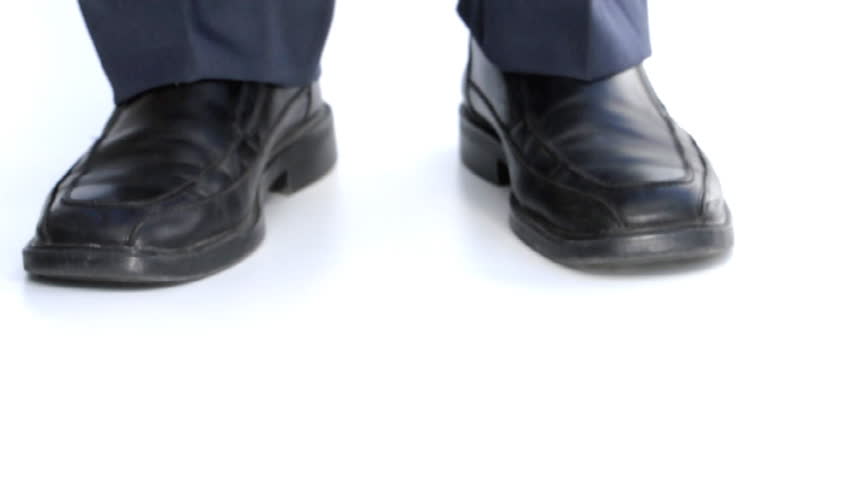 Closeup of cookie crumbs falling to white floor in front of businessman ("Tough cookie to crumble")