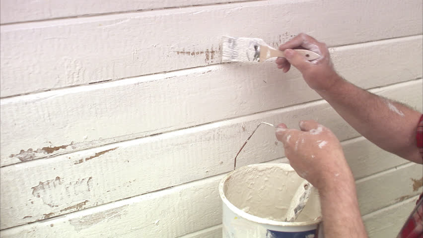 Elderly man painting his summer cottage