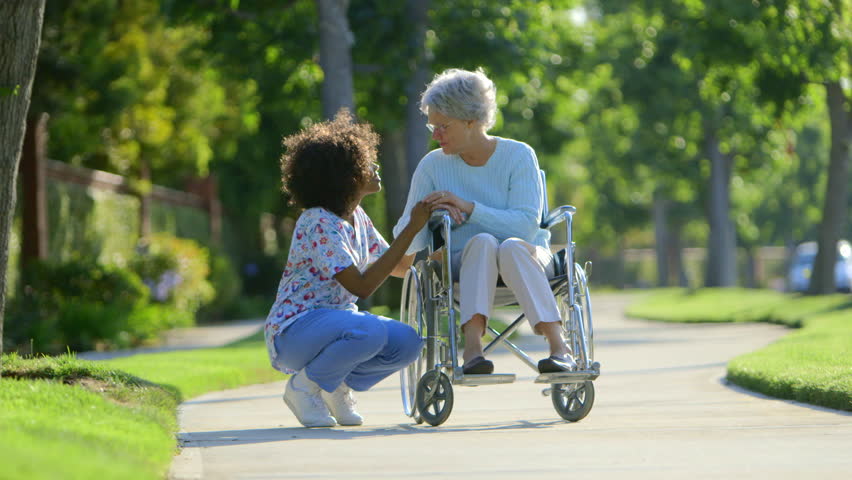 Nurse talking with elderly woman in wheelchair