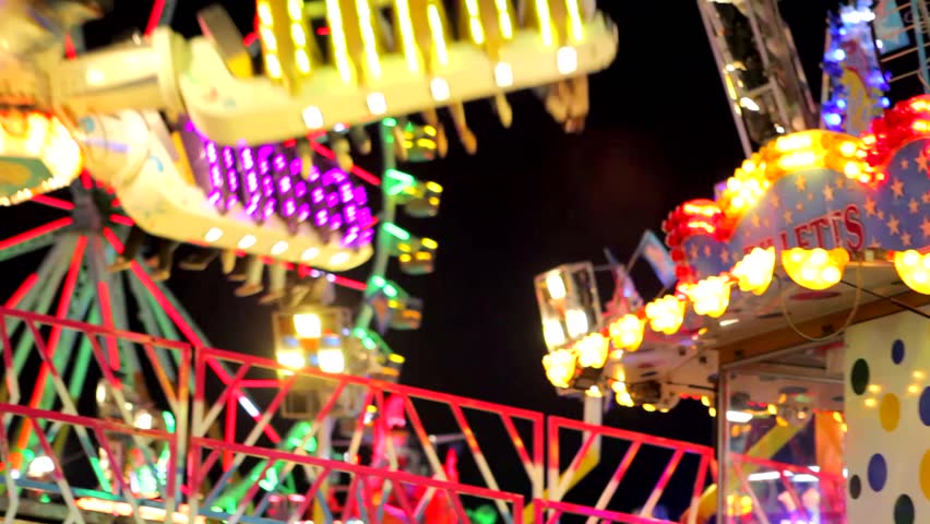 Panning view of a colorful fun fair ride at night. 
