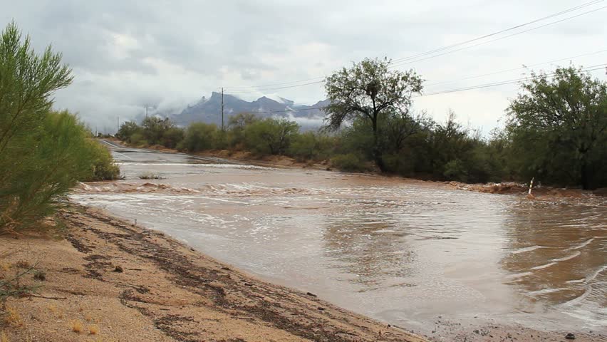 Rainwater gushes onto road from overflowing desert wash, causes flash flooding after monsoon, summer storm in Tucson, Arizona. 1080p