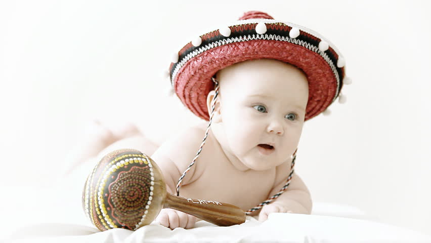 Baby in sombrero hat with maracas on the light background