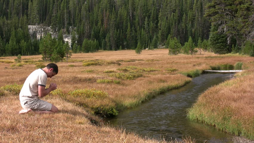 Man worshiping god next to a creek.  HD 1080i