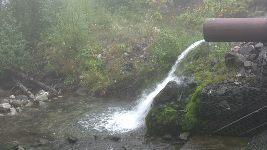 Water flowing from a large metal pipe with ambient sound.  HD 1080i