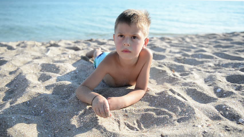 Child writes letters on sand