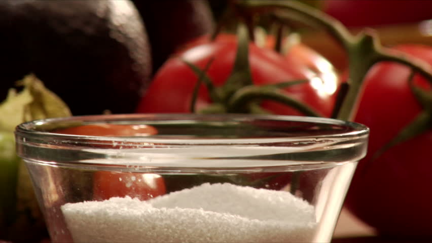 pan left to right over vegetables of a hand reaching for a pinch of salt