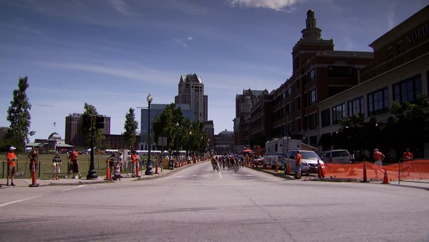 PROVIDENCE, RHODE ISLAND - SEPTEMBER 3, 2009: Large pack of bicycle racers passing camera with city skyline in background - slow motion