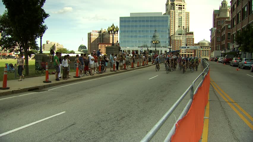 PROVIDENCE, RHODE ISLAND - SEPTEMBER 3, 2009: Women bicycle racers passing camera - wide shot with city skyline