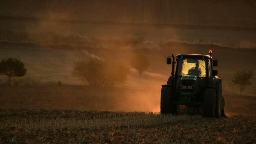 Tractor working in the field at sunset