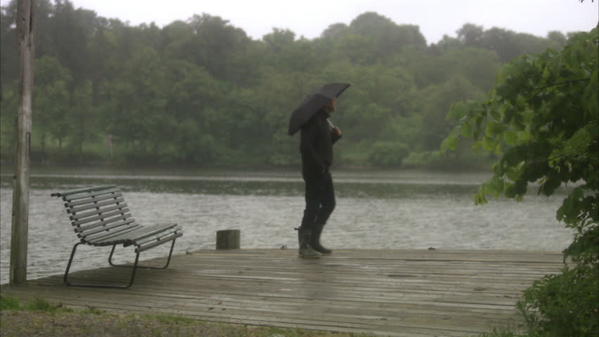 A man with an umbrella walking by water