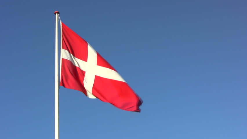The Danish flag, the Dannebrog, in wind gusts against a blue sky 