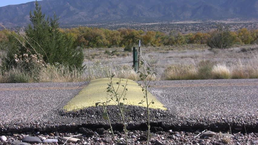 HD clip of car wheels going over a yellow speed bump in a desert road