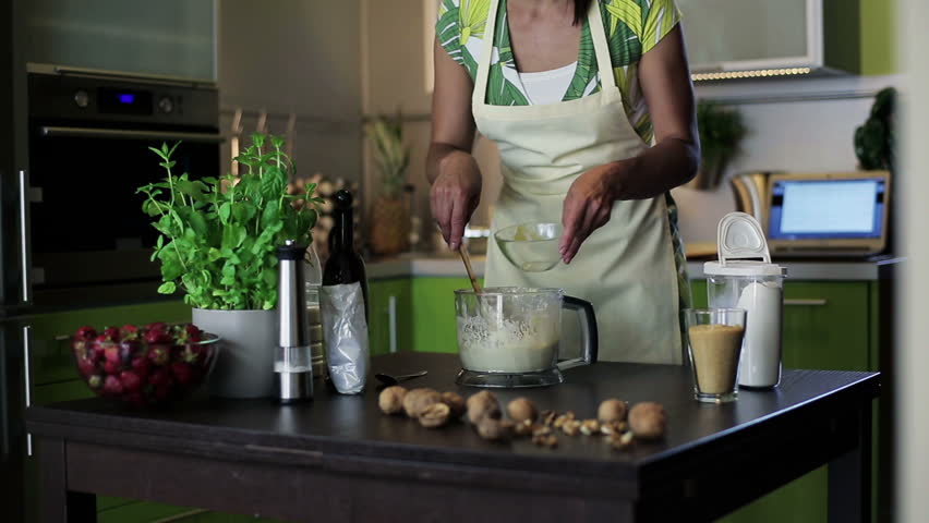 Woman checking recipe on laptop and adding egg to dough, dolly shot

