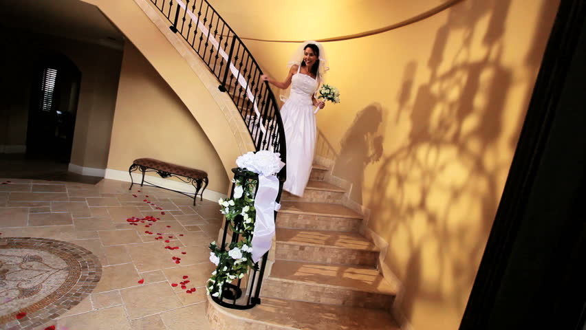 Beautiful bride wedding dress and veil descending marble staircase